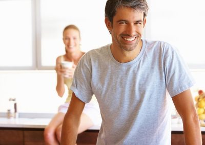 Casual man standing in the kitchen with his wife in the background