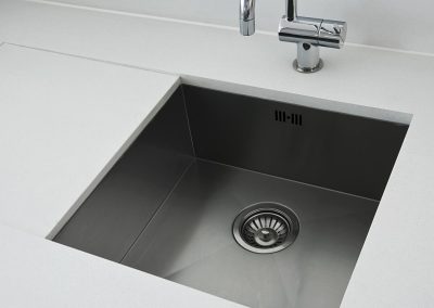 detail of a rectangular designer kitchen sink with chrome water tap